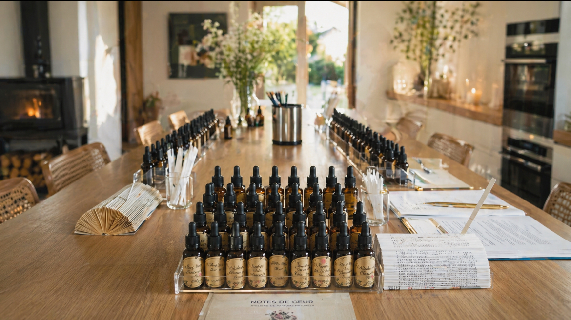 Table d'atelier dressée avec flacons d'huiles essentielles et bouquet de fleurs