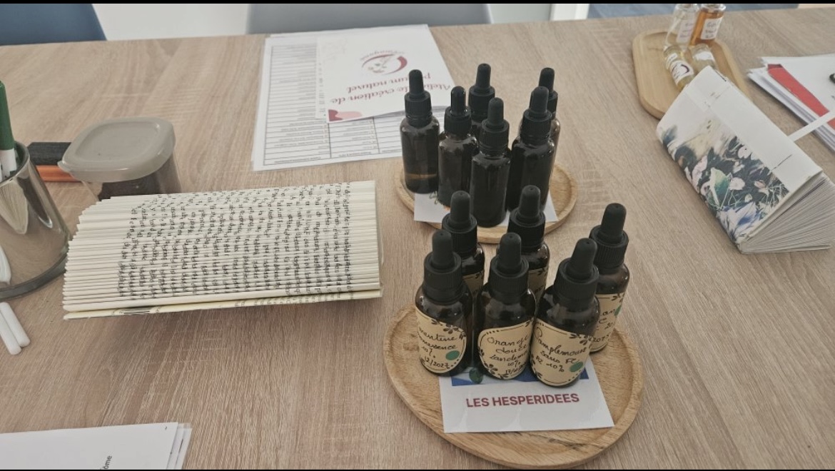 Table d'atelier avec flacons d'huiles essentielles, touches à sentir et fiche de composition